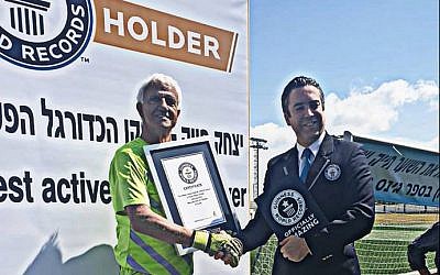 Isaak Hayik (left) presented with the  Guinness World Record for the oldest living active pro soccer player by an unidentified Guinness official, April 5, 2019 (Facebook)