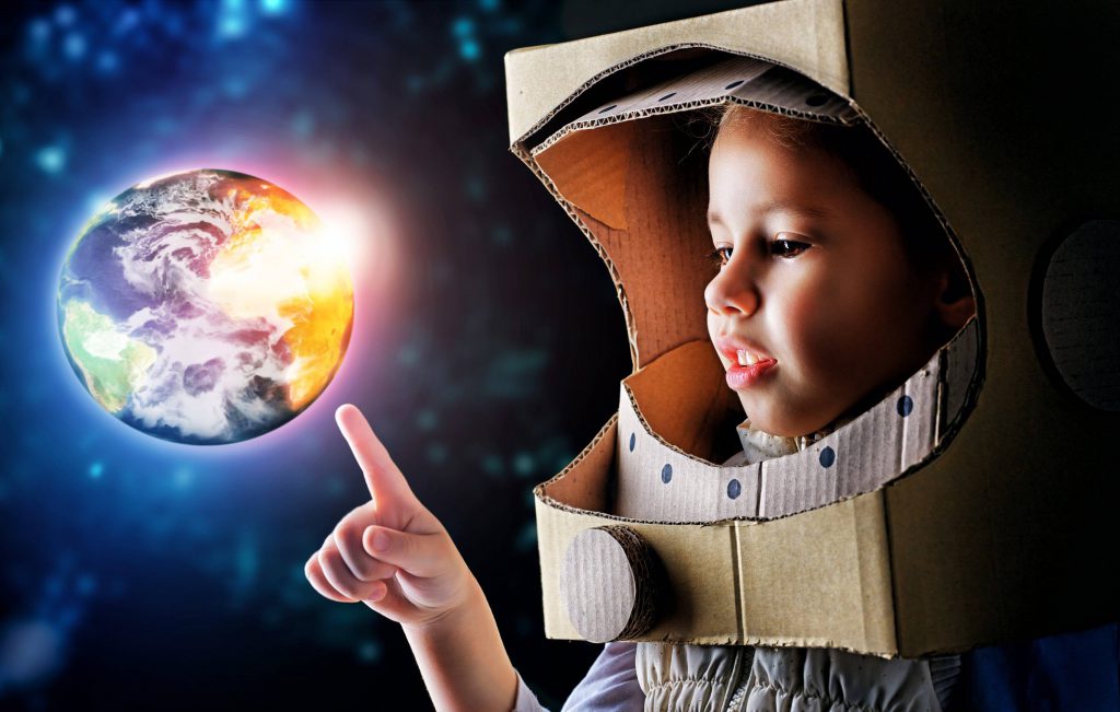 Young child reaching for bright globe.