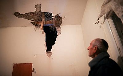 A man inspects the damage to his house caused from a rocket fired from the Gaza Strip, in the southern Israeli city of Sderot, near the border with Gaza late on March 25, 2019. (Hadas Parush/Flash90)