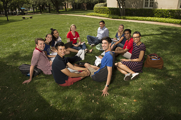 Group of students sitting down on grass.