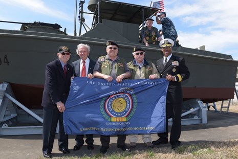 Vietnam veterans and Rear Admiral Jesse A. Wilson display a Commemorative banner