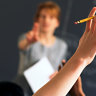 Teacher pointing to raised hands in classroom boarding school  Generic