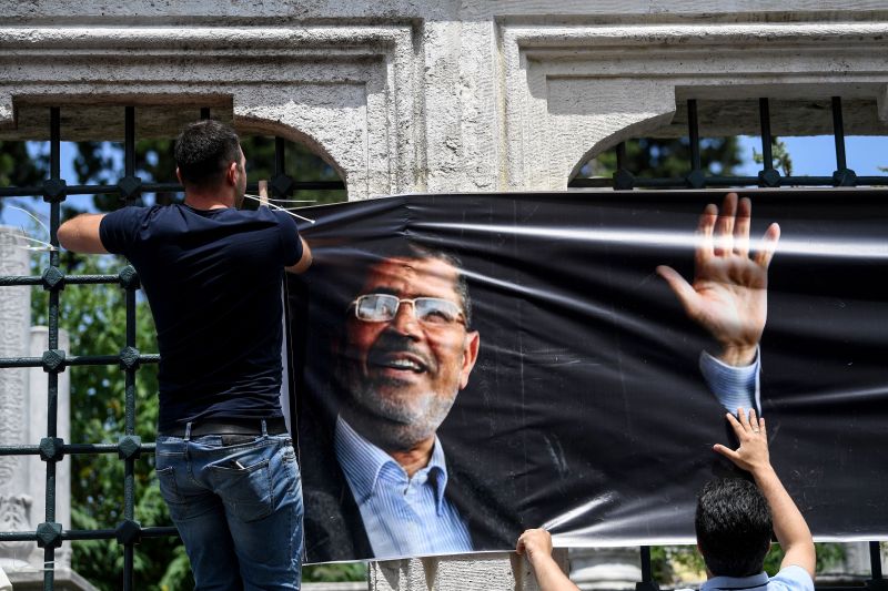 A man hangs a poster of Egyptian President Mohamed Morsi as people attend symbolic funeral cerenomy on June 18,2019 at Fatih mosque in Istanbul.