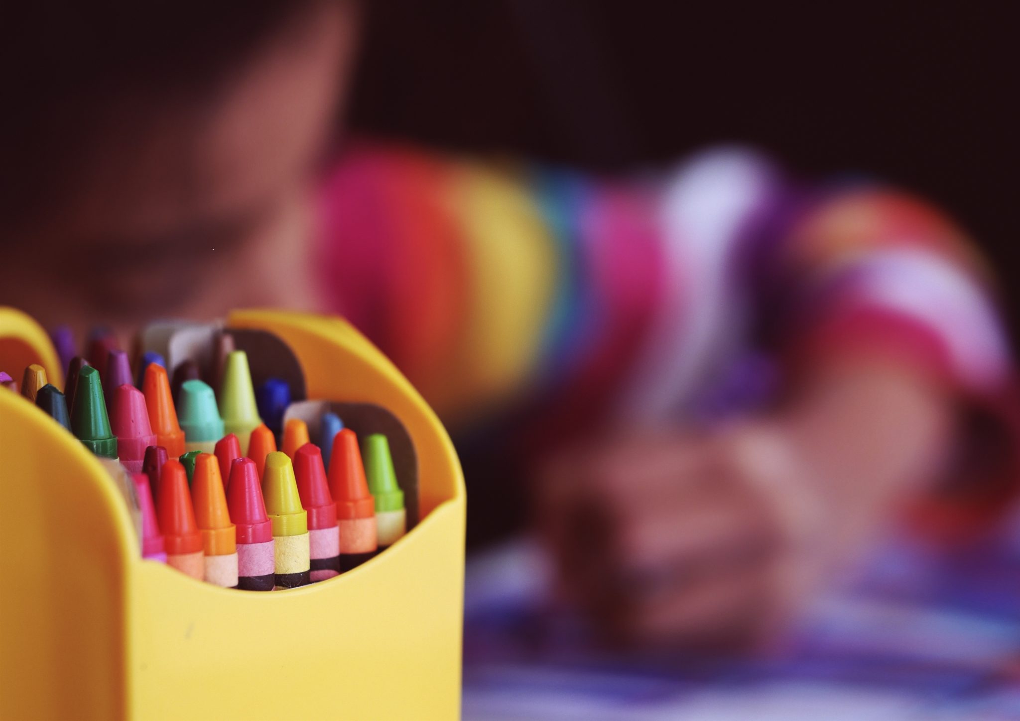 A child uses crayons to draw a picture