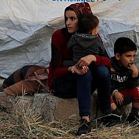 A Syrian woman with her children, who were displaced by the Turkish military operation in northeastern Syria, wait to receive a tent and other aid supplies at the Bardarash refugee camp, north of Mosul, Iraq, October 17, 2019. (AP Photo/Hussein Malla)