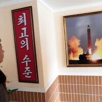 In this Nov. 26, 2019, photo, a man looks at a photo of the launch of a missile hanging on the wall of a factory workers' dormitory in Pyongyang, North Korea. (AP/Dita Alangkara)
