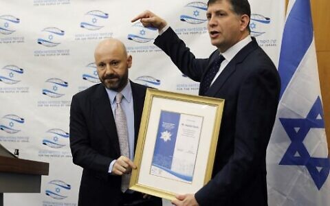 Lebanese-Swiss businessman Abdallah Chatila (L), who purchased items belonging to Adolf Hitler at a public auction in Europe to ensure that they do not get into neo-Nazi hands, receives from Sam Grundwerg, World Chairman of Keren Hayesod-UIA foundation, a certificate of appreciation at the Israeli fundraising association's headquarters in Jerusalem on December 8, 2019. (Photo by AHMAD GHARABLI / AFP)
