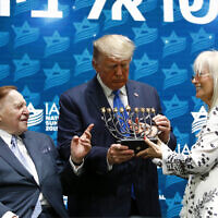 US President Donald Trump receives a menorah from Las Vegas Sands Corporation Chief Executive and Republican mega donor Sheldon Adelson, left, and his wife Miriam Adelson at the Israeli American Council National Summit in Hollywood, Florida., December 7, 2019. (AP/Patrick Semansky)