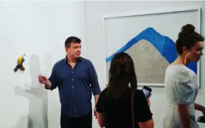 Performance artist David Datuna (L) moments before removing a $120,000 artwork -- a banana taped to a wall -- and eating it, at the Art Basel show in Miami Beach on December 8, 2019. (Screenshot: Instagram)
