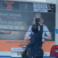 An ultra-Orthodox man vandalizing a campaign ad on a bus by tearing off the face of a woman from a poster, in footage published on December 8, 2019. (Screenshot: Twitter)