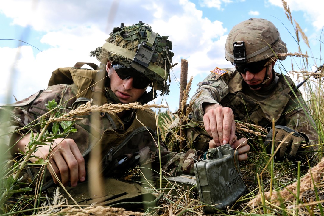 A U.S. and British soldier position an M18A1 Claymore mine.