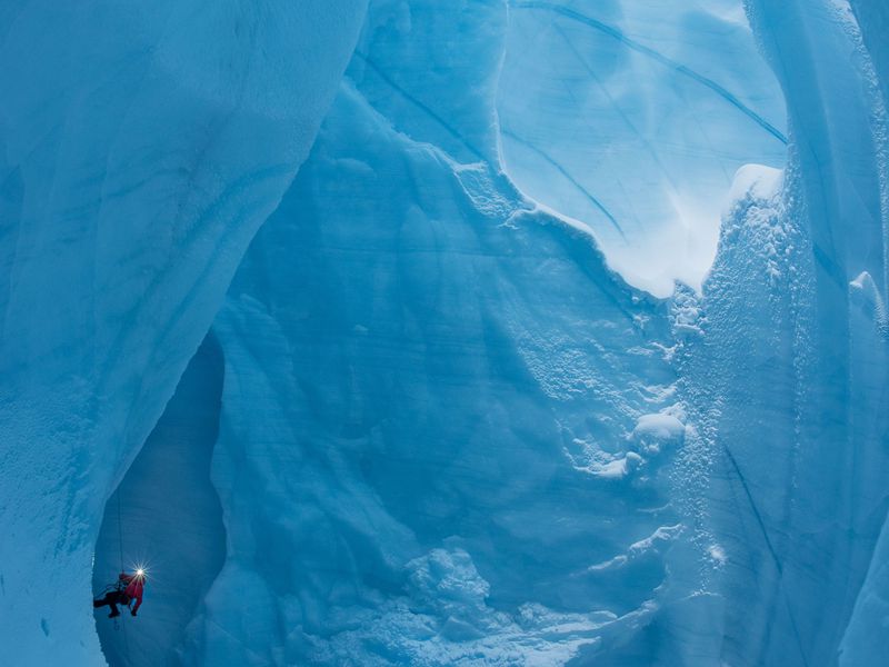 A caver climbs a nylon rope the exit a moulin on the Greenland Ice Sheet.