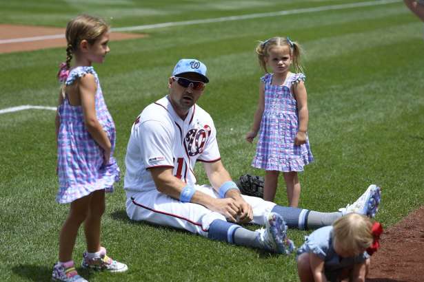 FILE - In this June 16, 2019, file photo, Washington Nationals' Ryan Zimmerman, center, sits on the field with his daughters Mackenzie, left, and Hayden, right, before a baseball game against the Arizona Diamondbacks in Washington. With baseball on hold because of the coronavirus pandemic, Zimmerman occasionally will offer his thoughts via diary entries published by the AP, while waiting for the 2020 season to begin.