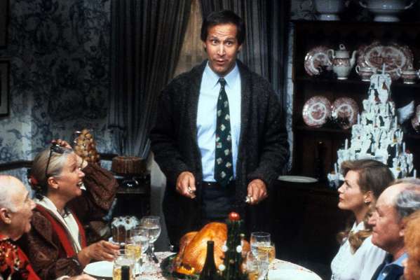 Chevy Chase stands at the head of the table in a scene from the film 'Christmas Vacation', 1989.