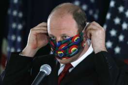 FILE-In this Thursday, May 28, 2020, file photograph, Colorado Governor Jared Polis puts on his face mask after a news conference about the state's efforts against the new coronavirus in Denver. During a news conference Tuesday, June 2, 2020, Polis said that the state is adding more than 800 new contact tracers to Colorado's coronavirus testing effort.