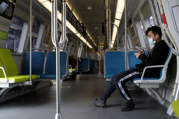A Bay Area Rapid Transit (BART) passenger wears a protective mask while riding on a train on April 08, 2020 in San Francisco, California. BART announced that it is slashing daily service as ridership falls dramatically due to the coronavirus shelter in place order. Starting Wednesday, regular Monday through Friday service will be reduced to running trains every half hour between 5 am and 9 pm.