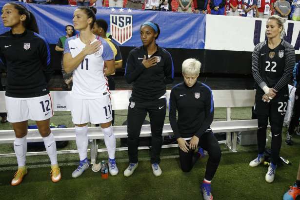 FILE - In this Sept. 18, 2016, file photo, United States' Megan Rapinoe, right, kneels next to teammates Christen Press (12), Ali Krieger (11), Crystal Dunn (16) and Ashlyn Harris (22) as the national anthem is played before the team's exhibition soccer match against the Netherlands in Atlanta. The U.S. women's national team wants the U.S. Soccer Federation to repeal the anthem policy it instituted after Rapinoe started kneeling during the national anthem. The U.S. women's team also wants the federation to state publicly that the policy was wrong and issue an apology to the team's black players and supporters.