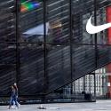 People wearing protective face masks walk past the closed Nike store on a nearly empty 5th Avenue