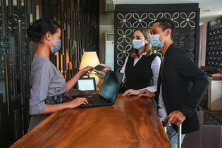 man and woman in mask checking into a hotel