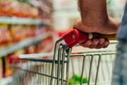 Shopping cart in supermarket. Caucasian or latin man hands hold shopping trolley in supermarket aisle.