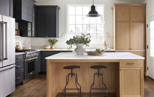 Cabinetry is a combination of white oak with a light natural finish and painted dark charcoal; some cabinets have glass doors for display. A built-in 