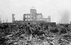 On Sept. 8, 1945, an allied correspondent stands in a sea of rubble before the shell of a building that once was a movie theater in Hiroshima, western