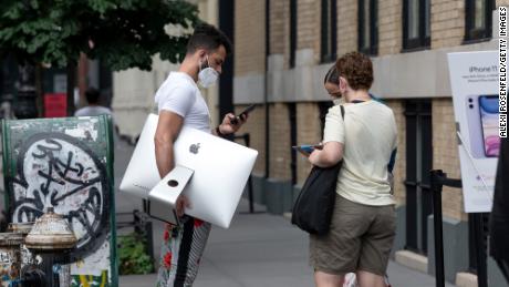 A man wearing a mask carries an Imac computer while waiting outside the Apple Store in SoHo as the city continues Phase 4 of re-opening following restrictions imposed to slow the spread of coronavirus on July 28, 2020 in New York City. The fourth phase allows outdoor arts and entertainment, sporting events without fans and media production. (Photo by Alexi Rosenfeld/Getty Images)