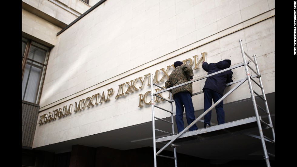 Nameplates on the front of the Crimean parliament building get removed Tuesday, March 18, in Simferopol.