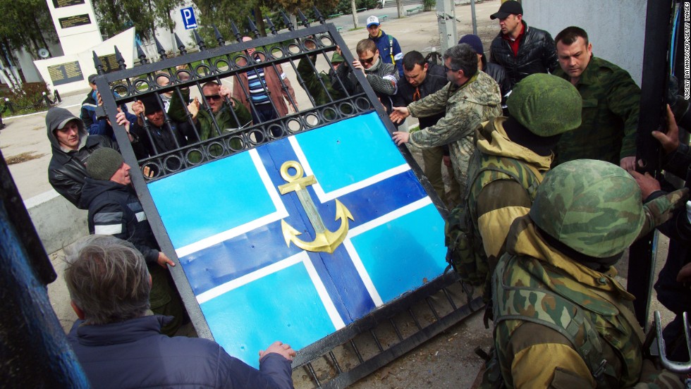 Pro-Russian protesters remove the gate to the Ukrainian navy headquarters as Russian troops stand guard in Sevastopol on Wednesday, March 19.