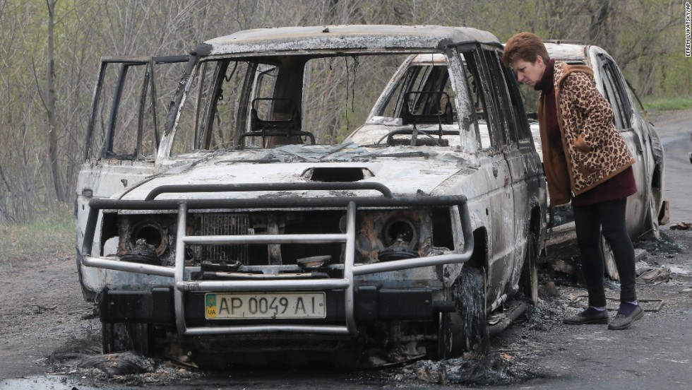 A resident inspects burnt-out cars at a roadblock on April 20. 