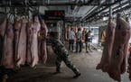 Workers unload pig carcasses at a warehouse that is part of China’s national pork reserve, in Beijing, Sept. 27, 2019. T