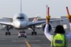 An aircraft marshall signals as an airbus taxis on the runway at Doha Airport in Qatar