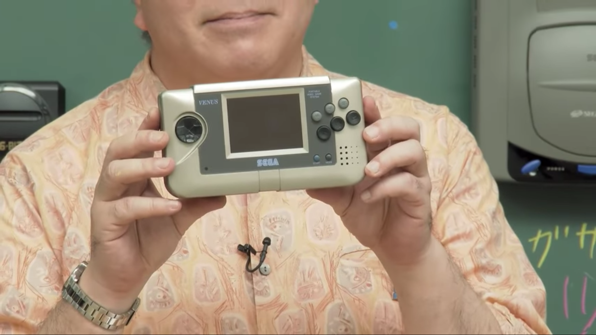 Close up of Hiroyuki Miyazaki’s hands holding the Sega Venus handheld prototype