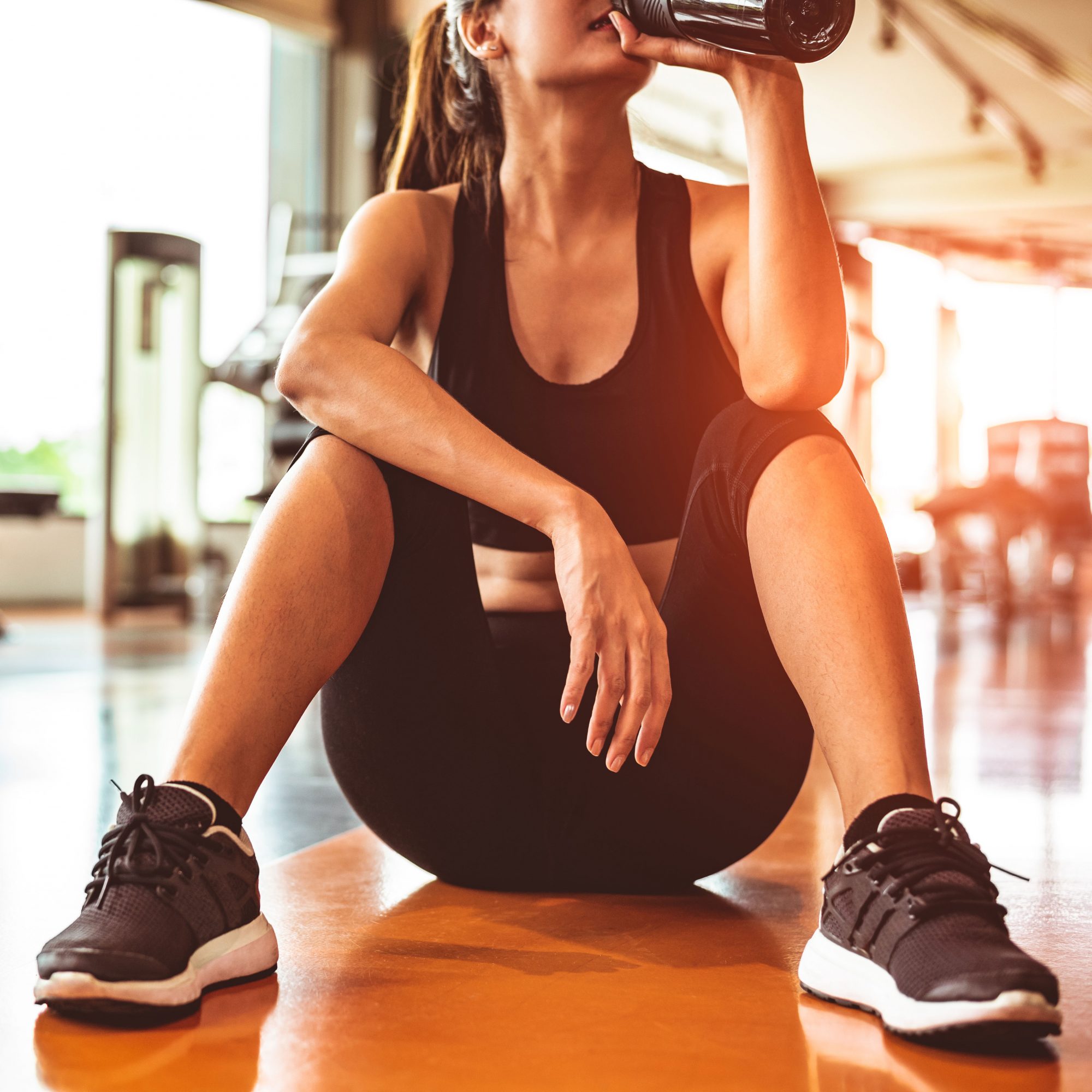 Close_Up_Of_Woman_Sitting_On_Gym_Floor_Drinking_Shake
