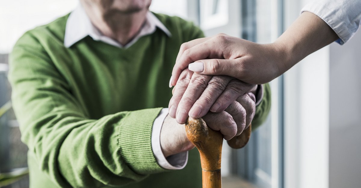 A woman holds the hand of an elderly man