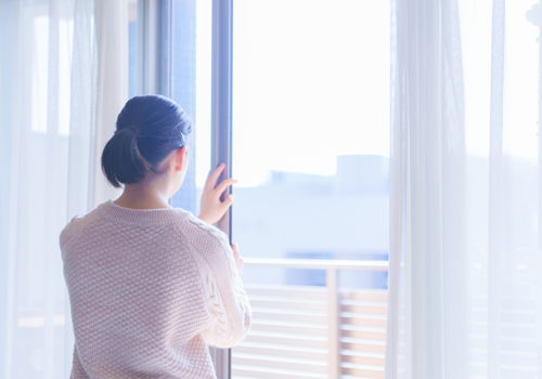 A woman looking through a glass door over a balcony
