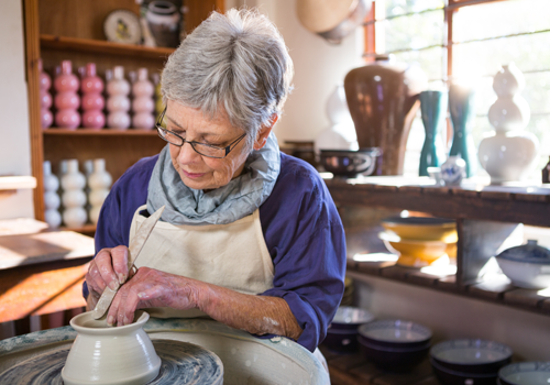 An older woman making pottery
