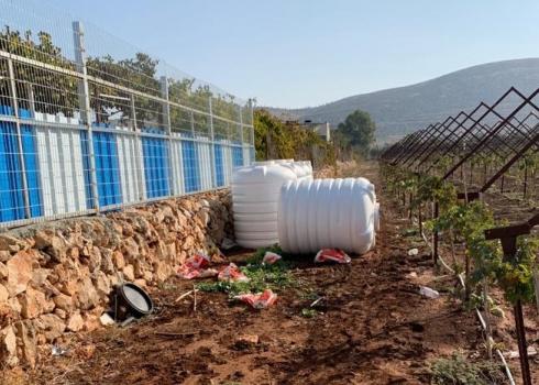 Damaged water containers in Nidal Rab’i’s plot, Turmusaya, 9 Nov. 2020. Photo by Firas ‘Alami 