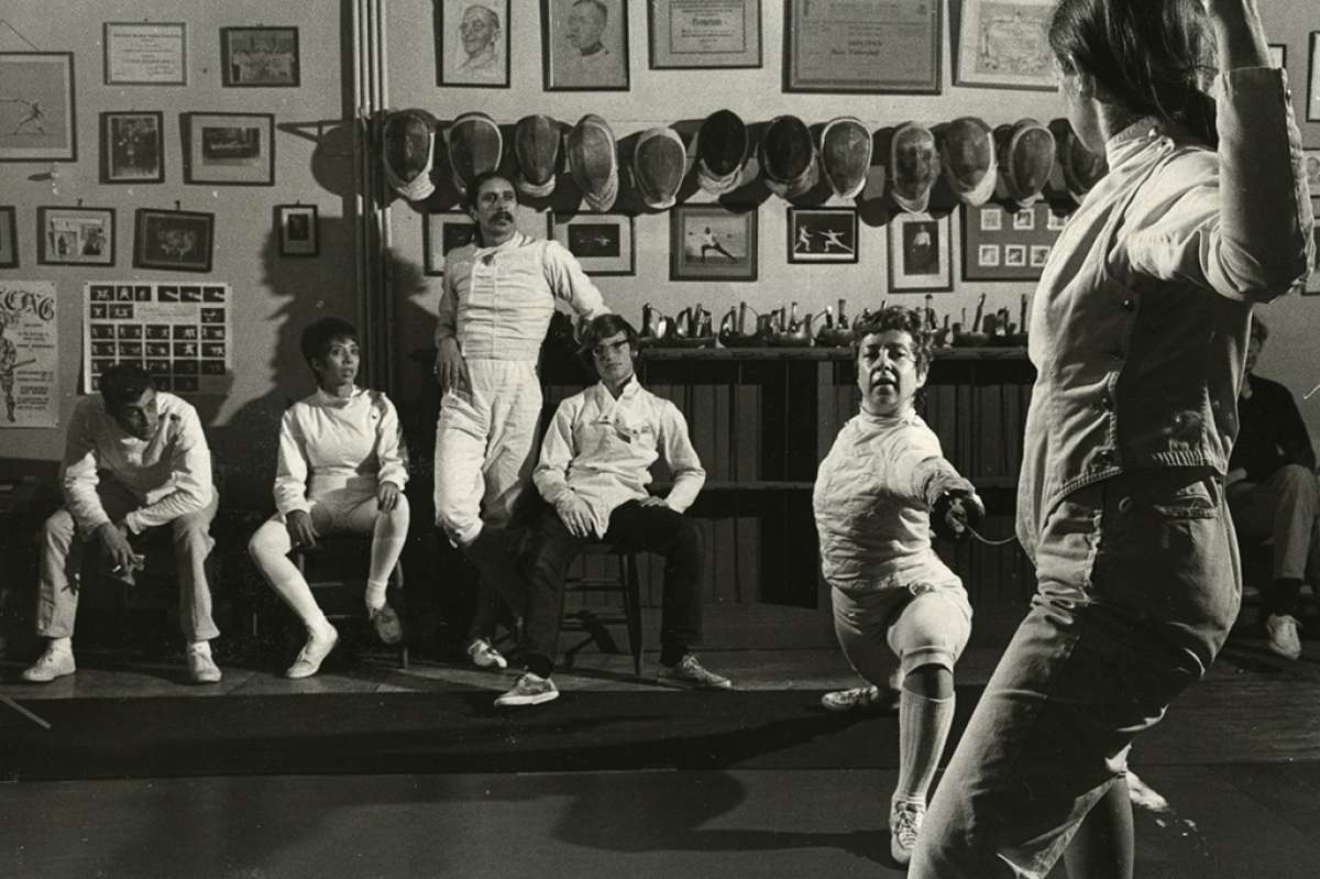 Michael D'Asaro standing in the center in the back at the Halberstadt fencing club. Three-time national foil champion Harriet King is demonstrating the lunge. She won two championships under D'Asaro's coaching.