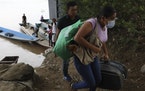 Venezuelans carry their belongings from a boat they used to cross the Arauca River to Colombia. Thousands of Venezuelans are seeking shelter in Colomb