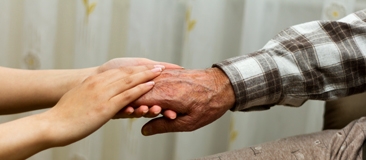 Younger hands holding an older person's hand
