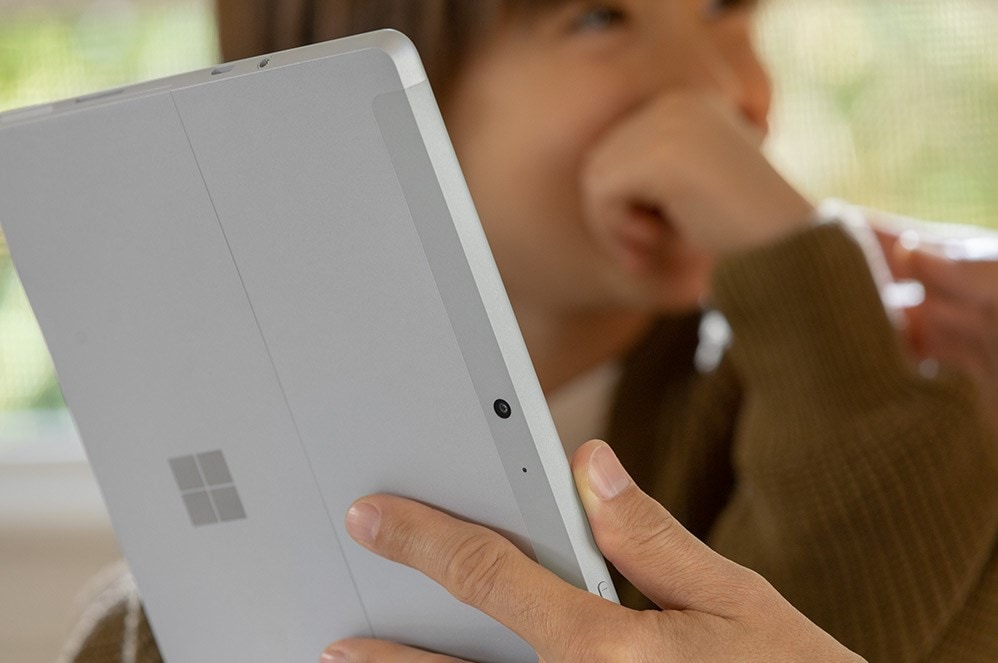 A woman holds Surface Go 2 while her young son looks on.