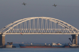 Russian jet fighters fly over a bridge connecting Russia with Crimea with a cargo ship blocking passage [File: Pavel Rebrov/Reuters]