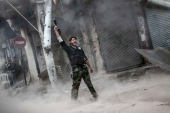 Ali, a rebel fighter, gestures for victory after firing a shoulder-fired rocket towards a building where Syrian troops loyal to President Bashar al-Assad were hiding as they attempted to gain terrain against the rebels during heavy clashes in the Jedida district of Aleppo, Syria, on November 4, 2012 [Narciso Contreras]