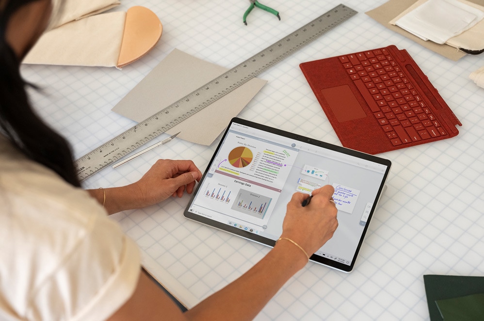 Surface Pro X held in tablet mode with Slim Pen by a person using Microsoft Word