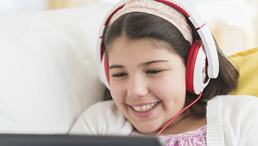 young girl using a laptop with headphones