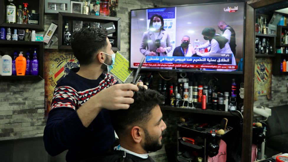 A barber watching Covid-19 news (Credit: Jaafar Ashtiyeh / Getty Images)
