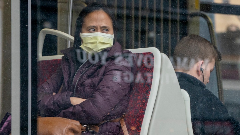 A woman wears a mask as she rides a TTC streetcar in Toronto on Friday, March 20, 2020.  THE CANADIAN PRESS/Frank Gunn