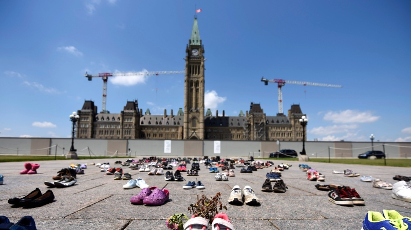 Dried flowers rest inside a pair of child's running shoes at a memorial for the 215 children whose remains were found at the grounds of the former Kamloops Indian Residential School at Tk’emlups te Secwépemc First Nation in Kamloops, B.C., on Parliament Hill in Ottawa on Friday, June 4, 2021. THE CANADIAN PRESS/Justin Tang 