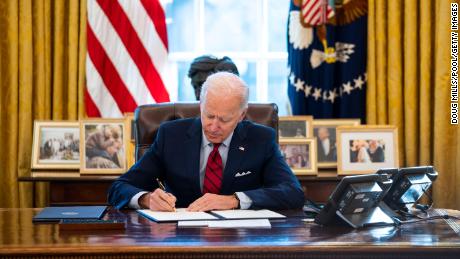 U.S. President Joe Biden signs executive actions in the Oval Office of the White House on January 28, 2021 in Washington, DC. President Biden signed a series of executive actions aimed at expanding access to health care, including re-opening enrollment for health care offered through the federal marketplace created under the Affordable Care Act.